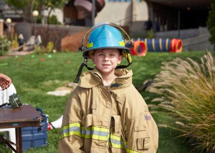 Boy dressed up in fire fighting gear.