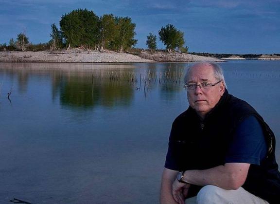 David Hayden, Photographer in Residence poses by a lake.