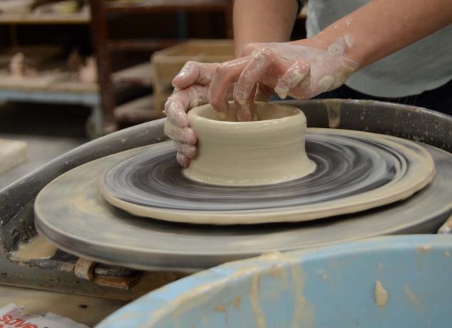 Person making pottery on the wheel.